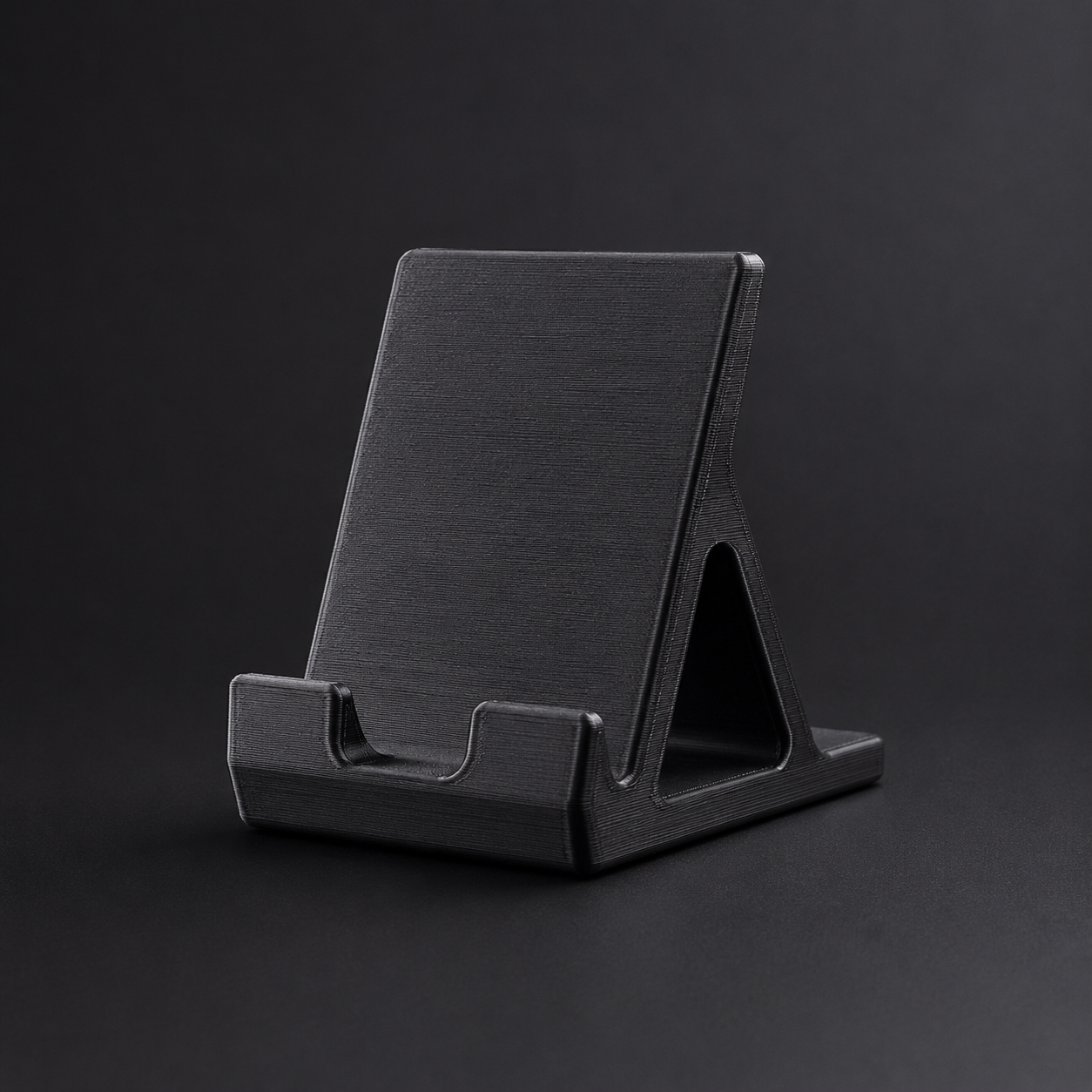 Black 3D-printed phone stand on a dark studio background